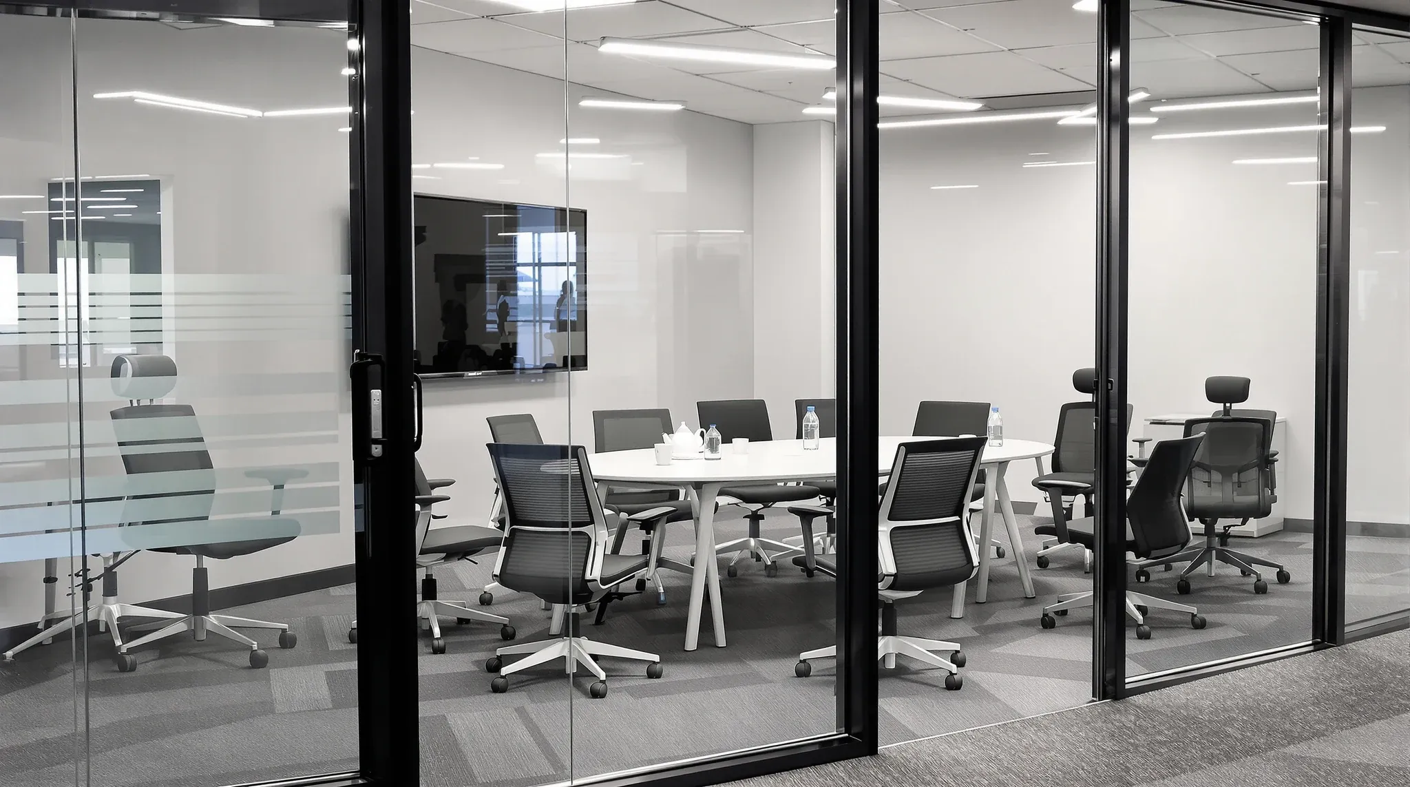 A small meeting room crammed with extra chairs around a table meant for four