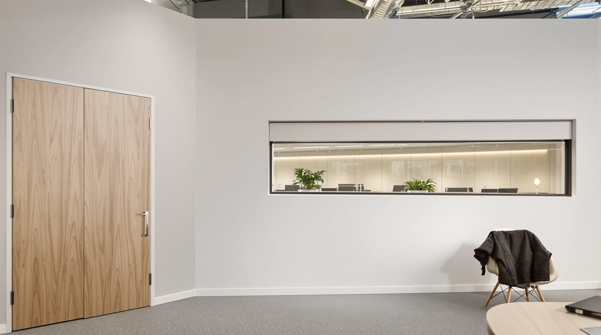 A solid plasterboard meeting room wall meeting a wall with a long internal window into a team room