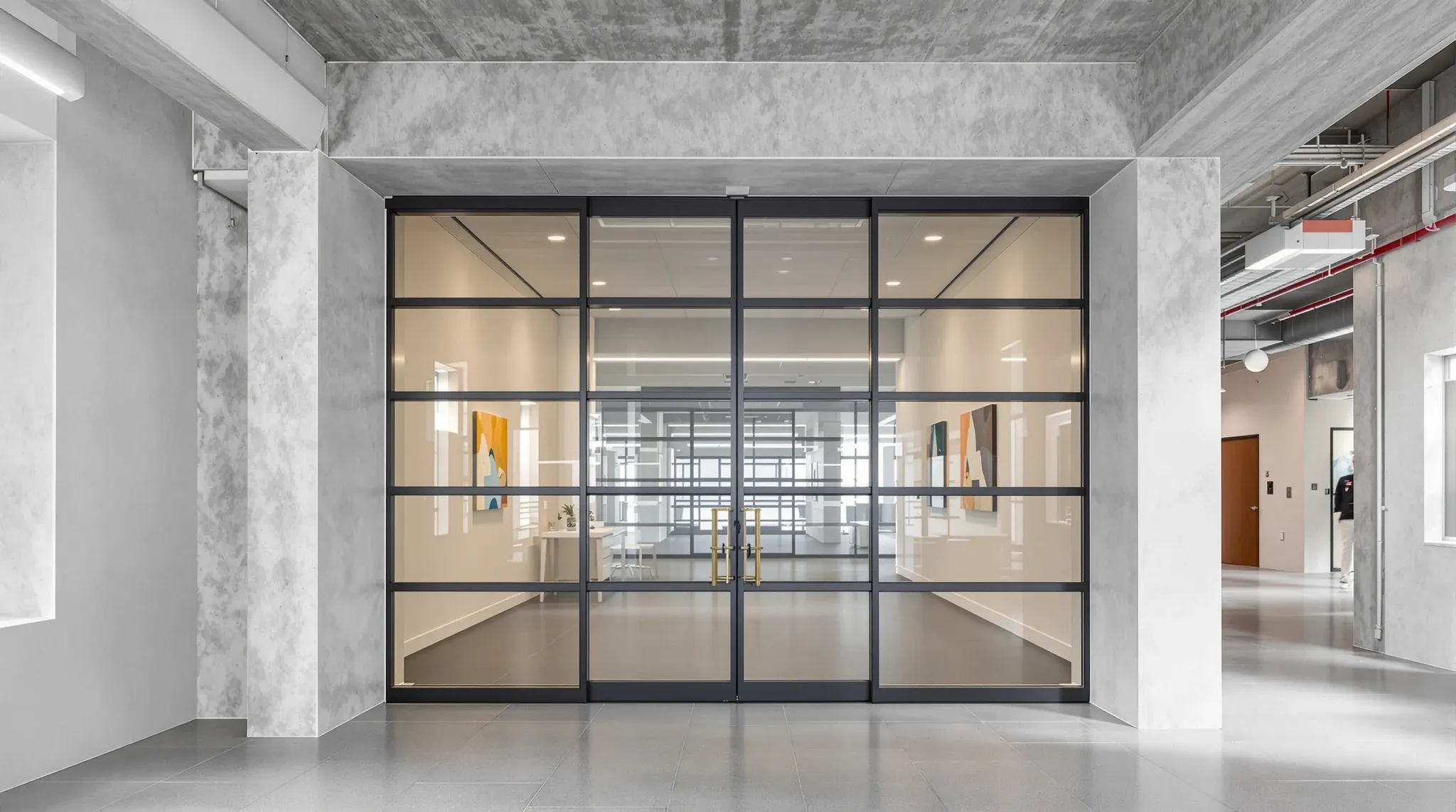 A full height glazed office door rising to an exposed concrete soffit