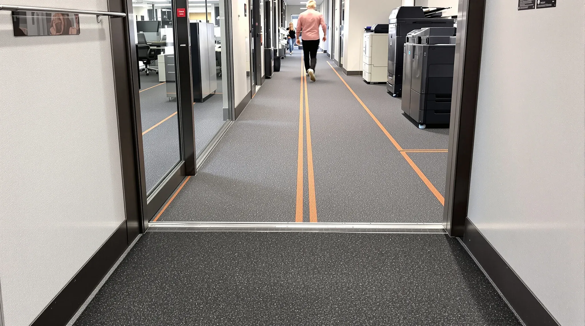A recessed entry mat leading into a well-used carpet tile corridor from a lift lobby