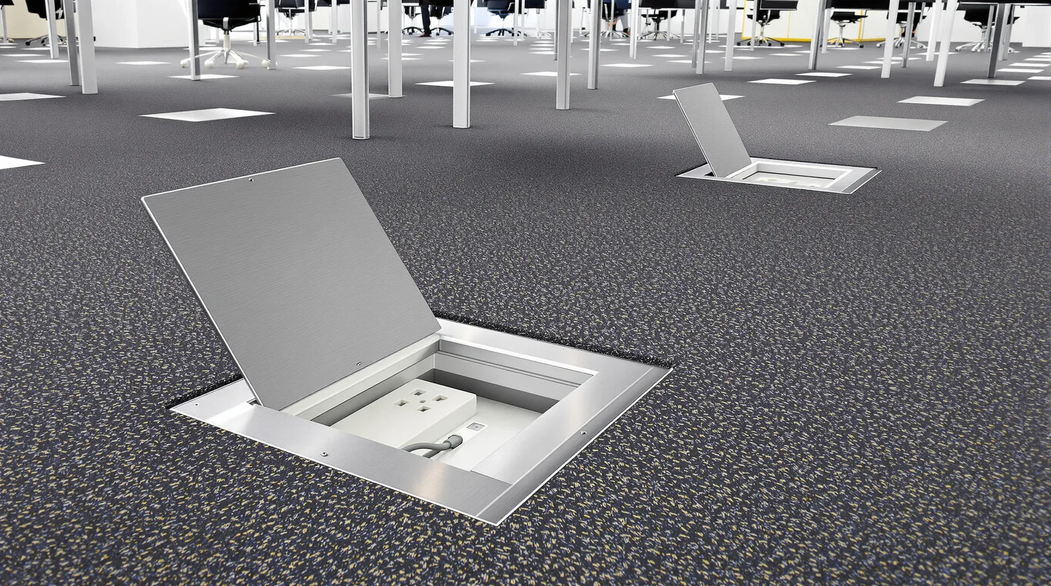 An open floor box set into office carpet tiles, with more flush lids spaced across the floor