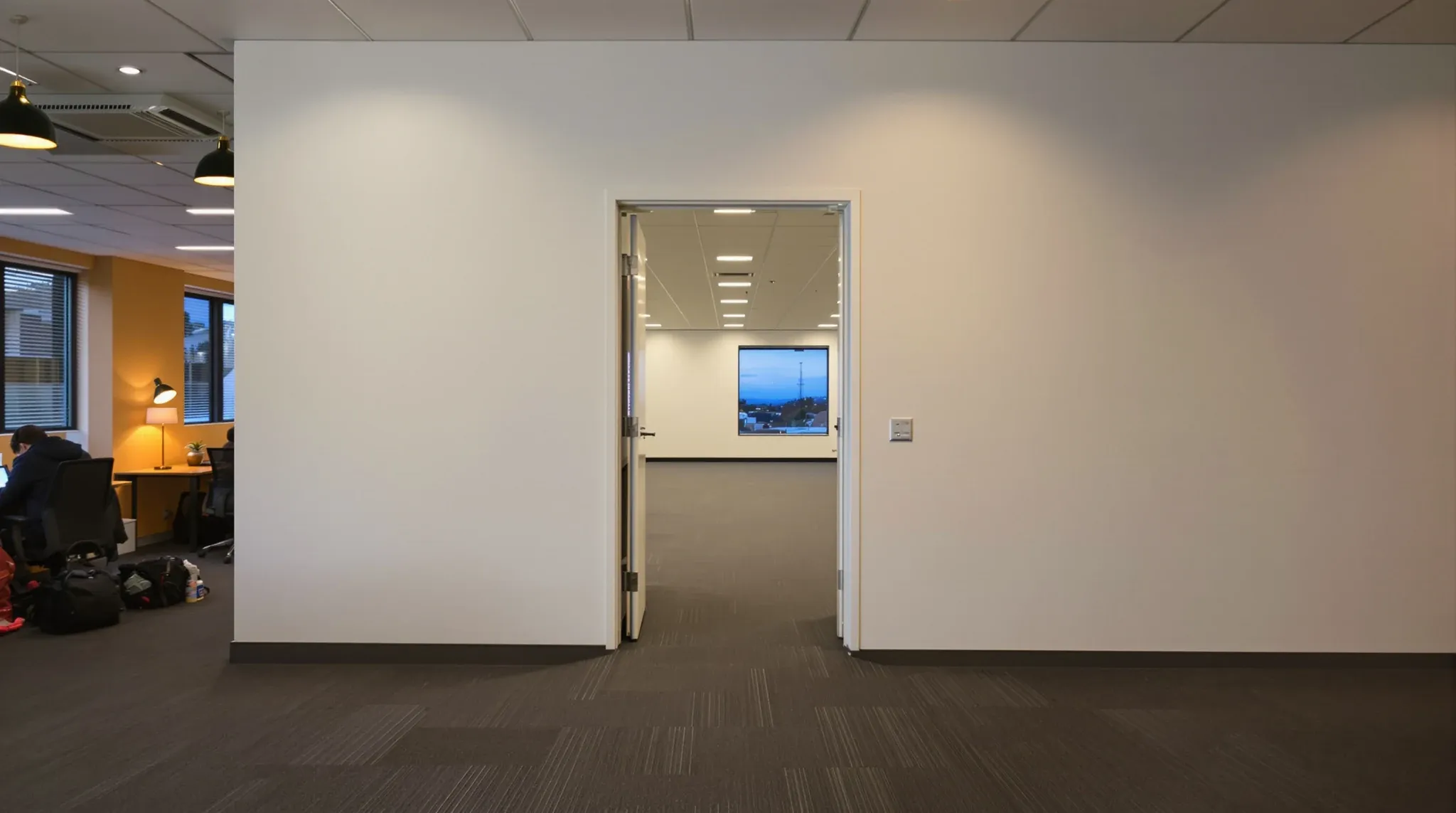 Through an open door in a new dividing wall, the empty half of an office floor ready for a subtenant
