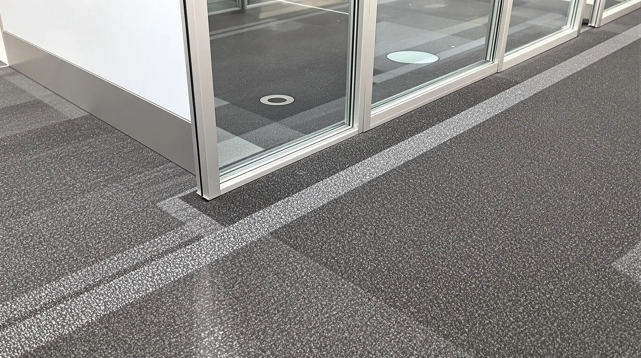 Faded carpet lines and fixing holes left where a modular partition once stood, beside its new position