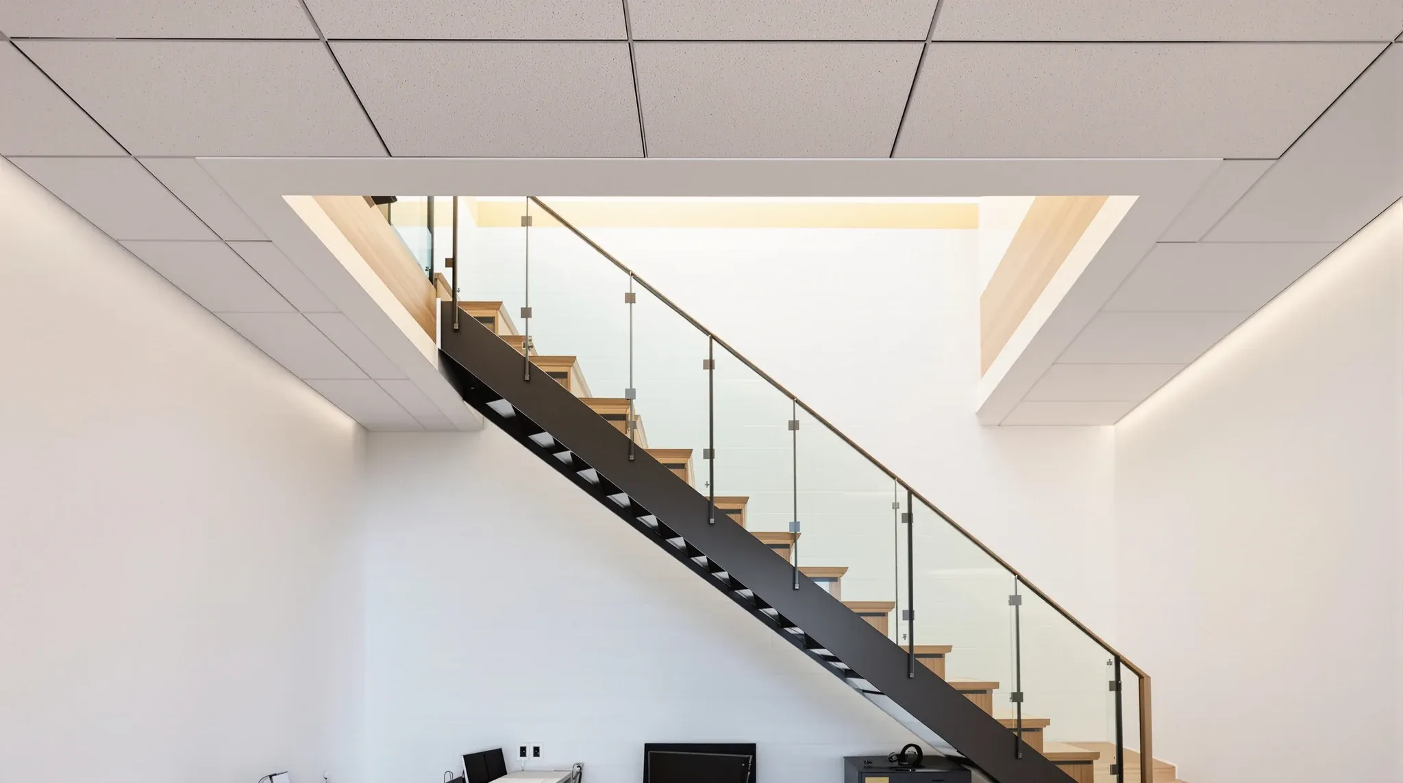 A straight internal stair rising through a neat plasterboard-lined opening in an office ceiling