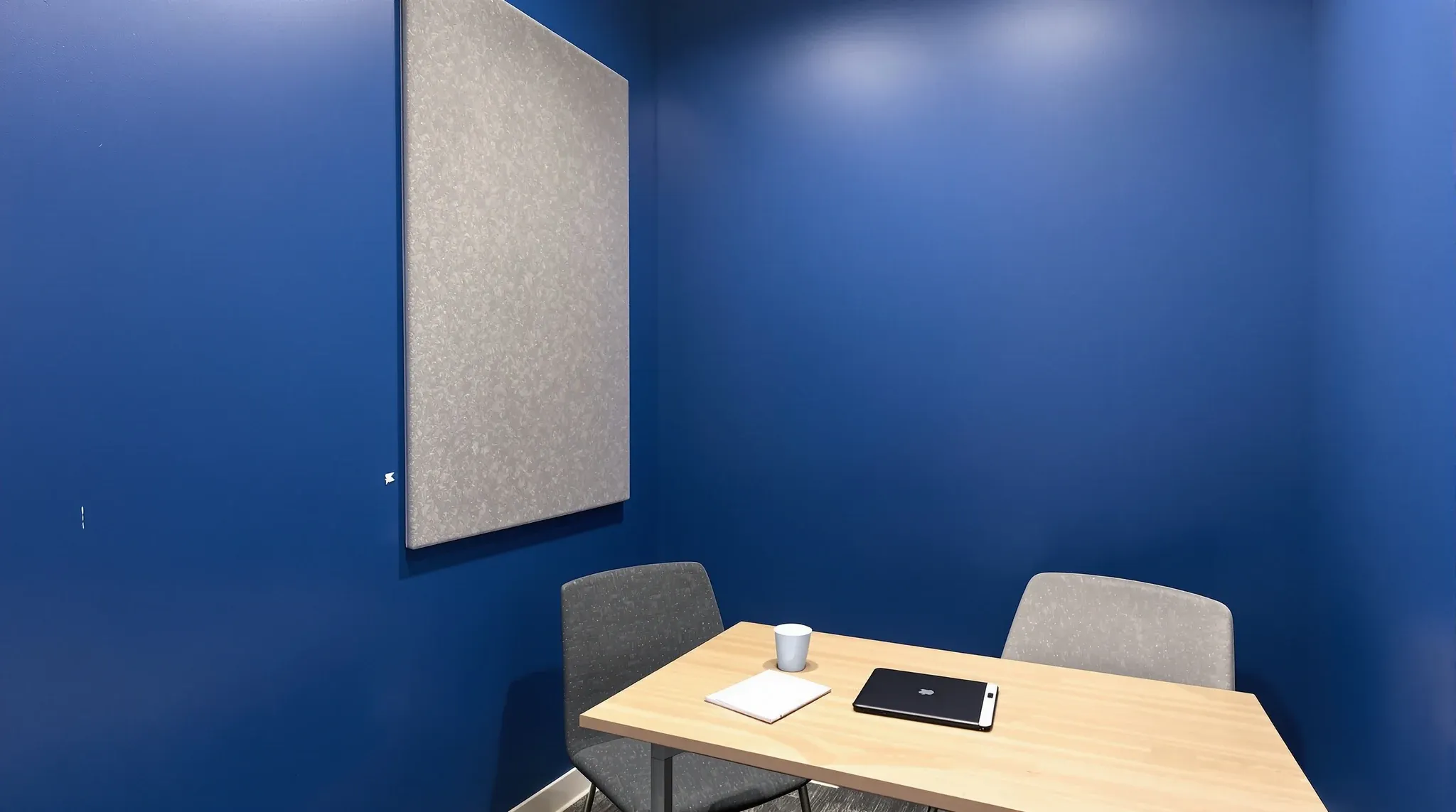 A well-used small meeting room with deep blue plasterboard walls and a closed door