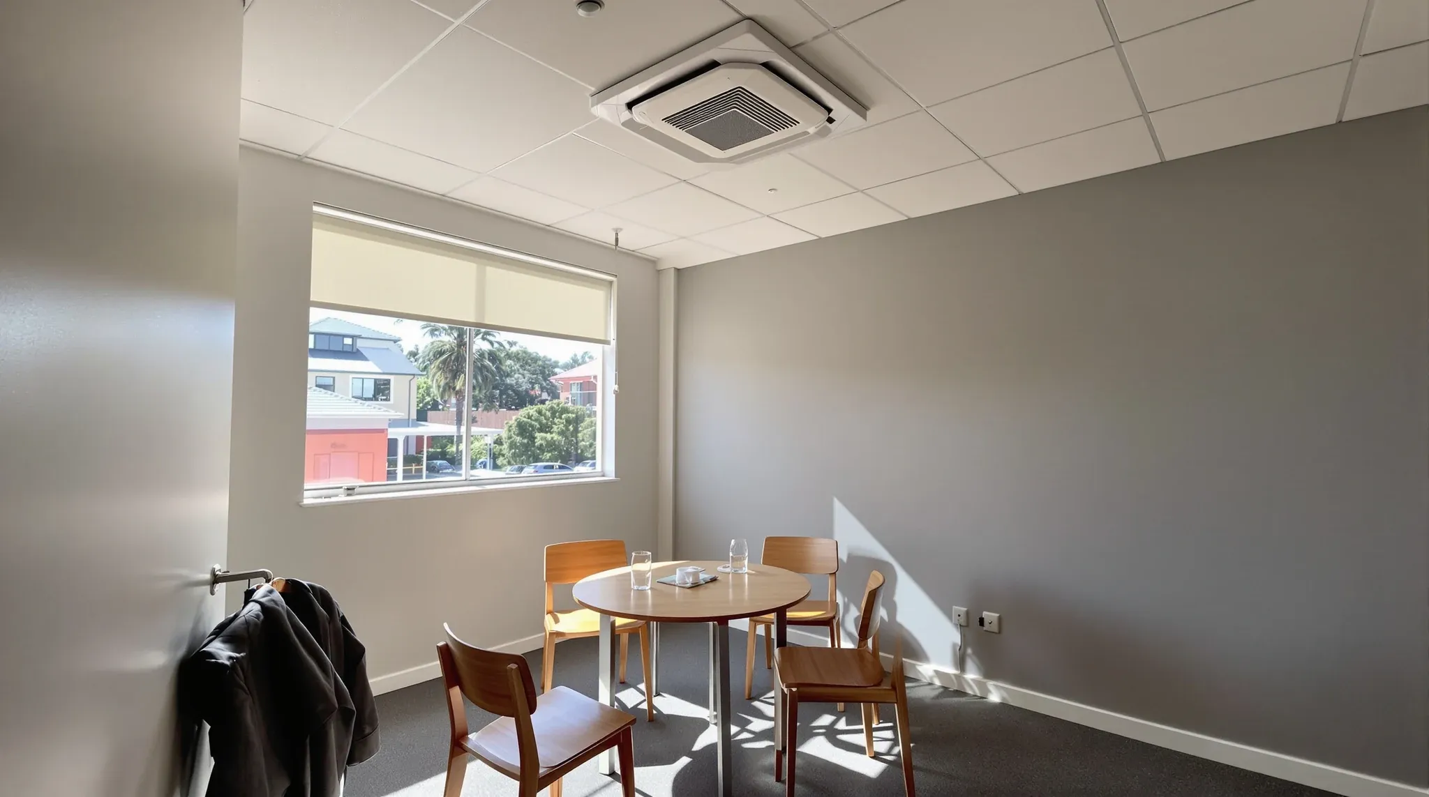 A small office meeting room on a hot afternoon with a square air conditioning unit set into the ceiling
