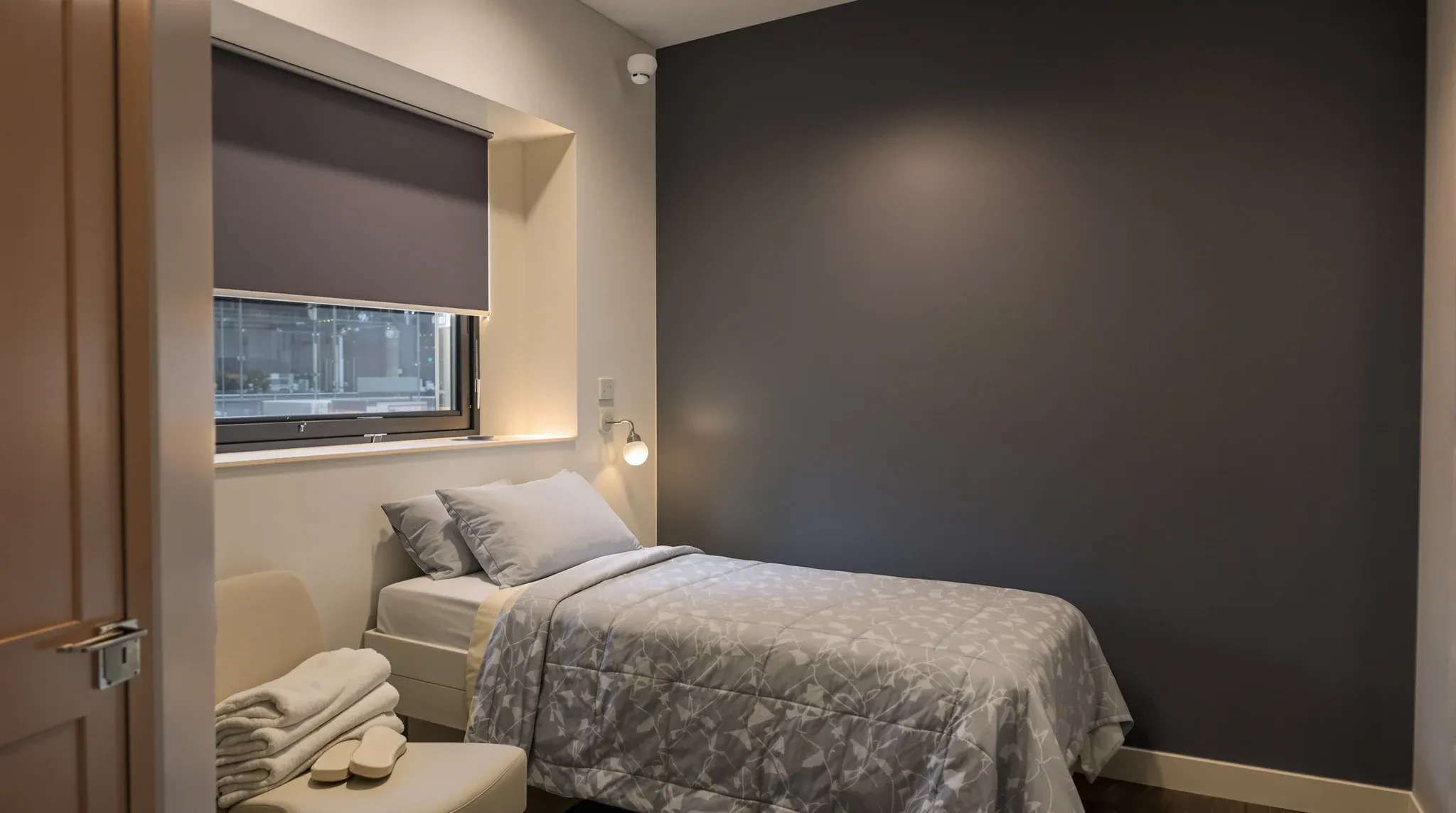 Sleep study bedroom in a commercial suite with blackout blinds, low bedside lighting and a wall-mounted patient panel