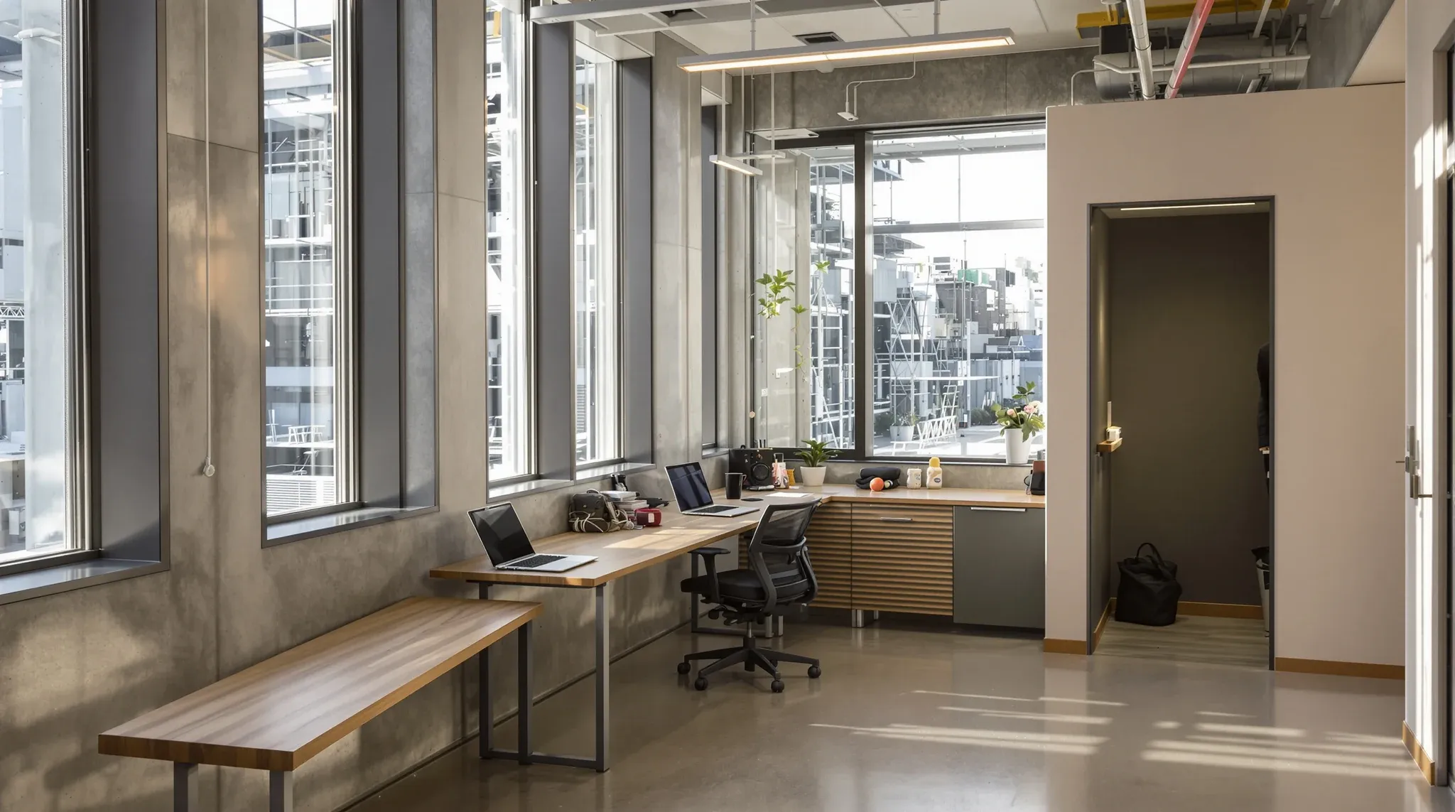 A small first private office with a long shared desk and a compact phone room in the corner