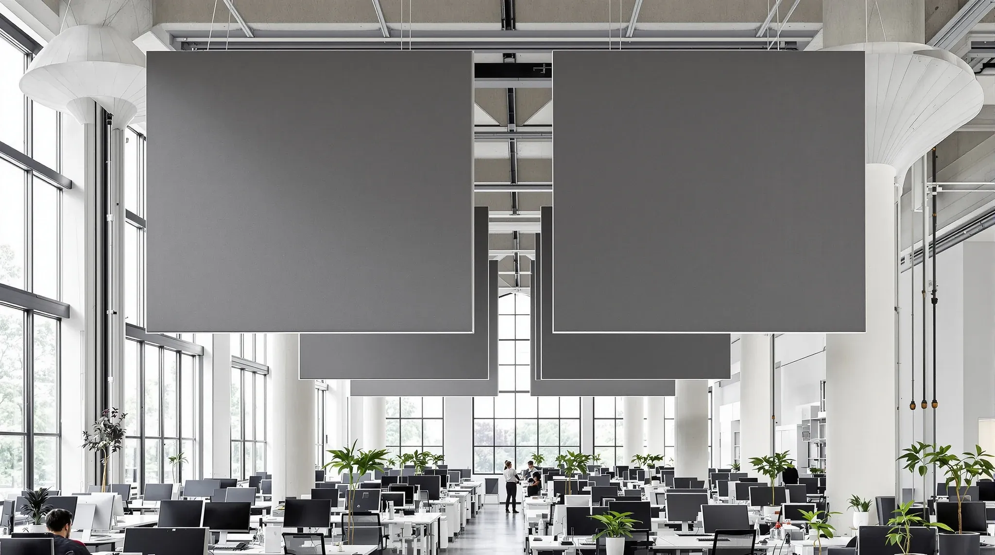 A tall former factory office with mushroom columns and a few large felt panels hung on wires over desks