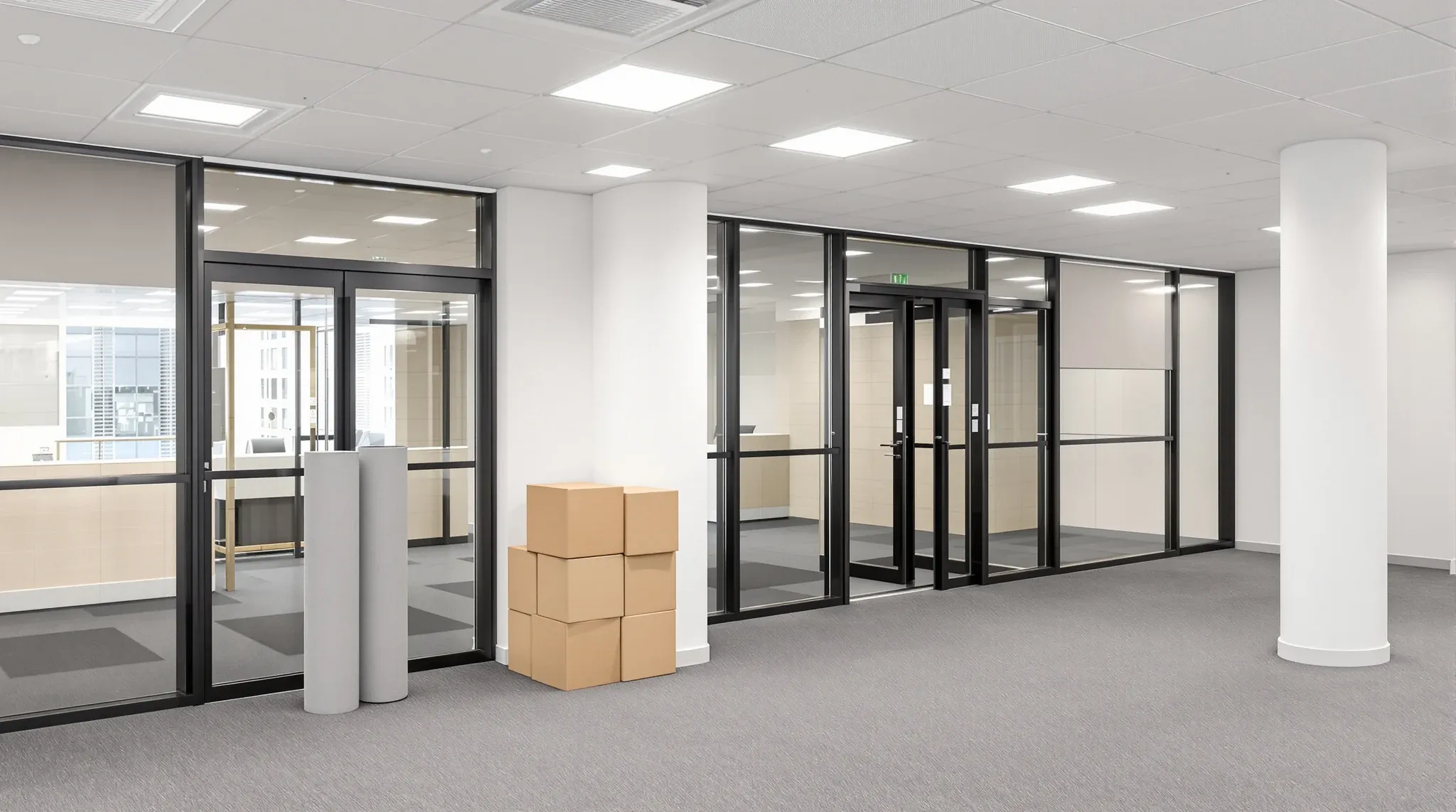 A returned, empty office tenancy by its glass entry doors, with floor protection rolled up and boxes stacked