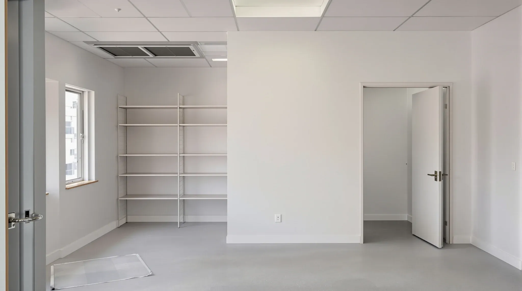 Empty finished office print and storage room with shelving, wide door, no labels