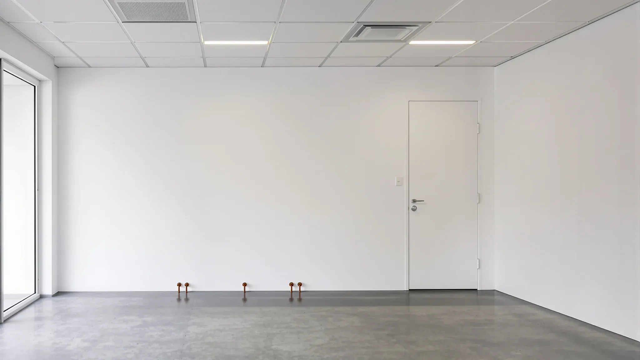 Empty shop after a salon make good, with capped water pipes low on the back wall and a clean concrete floor