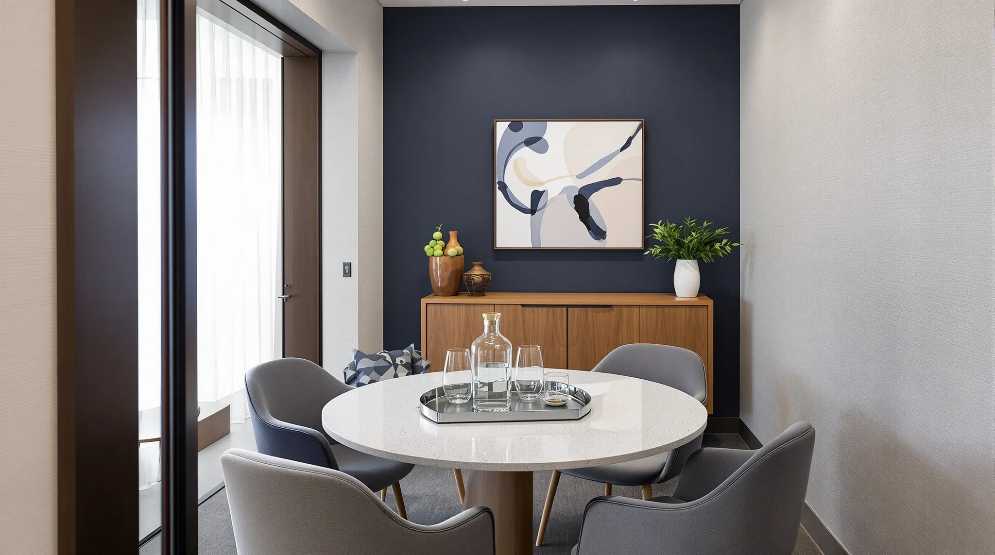 A small client meeting room set with a carafe and glasses, seen through the doorway