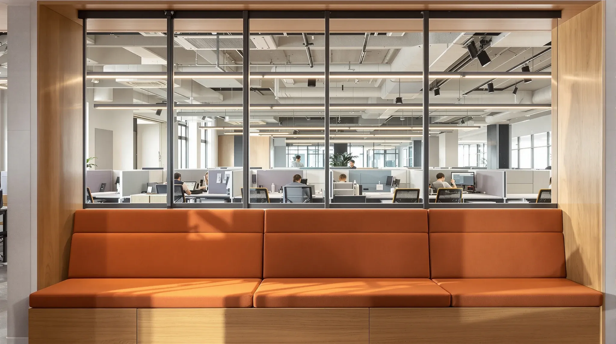 A newly refurbished breakout area with oak joinery beside older workstations in an existing office