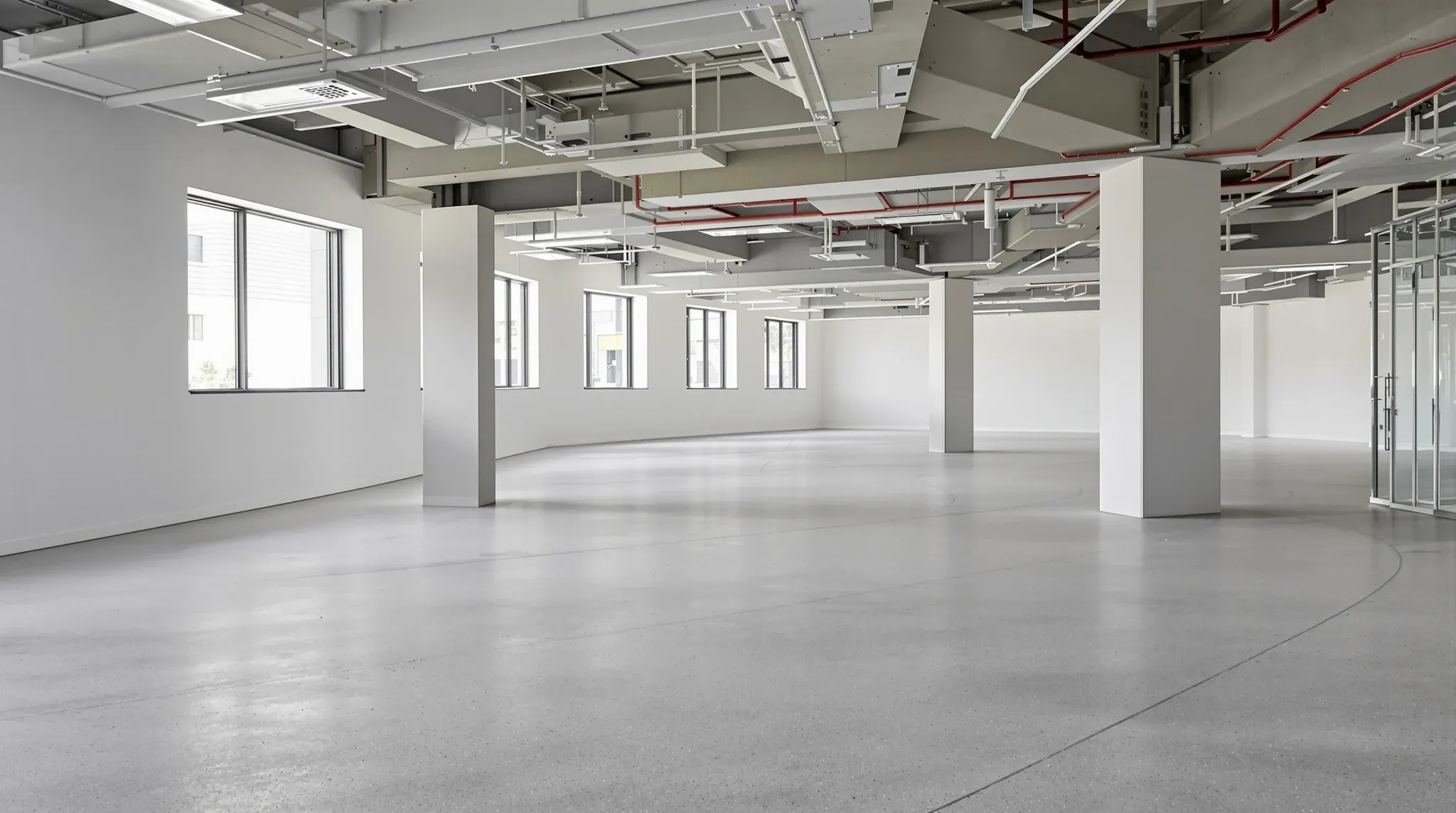 Empty concrete cold shell office floor with exposed services and windows