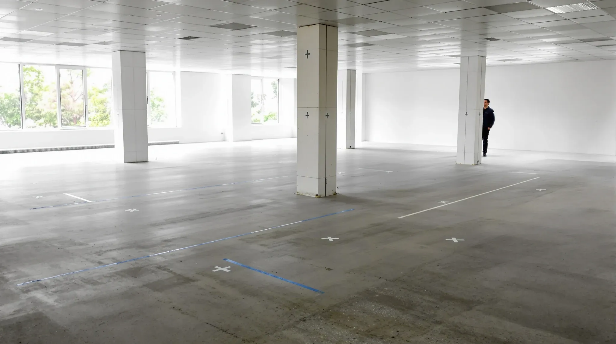 A stripped office floor with a few tape crosses and a chalk line marking out one group of desks