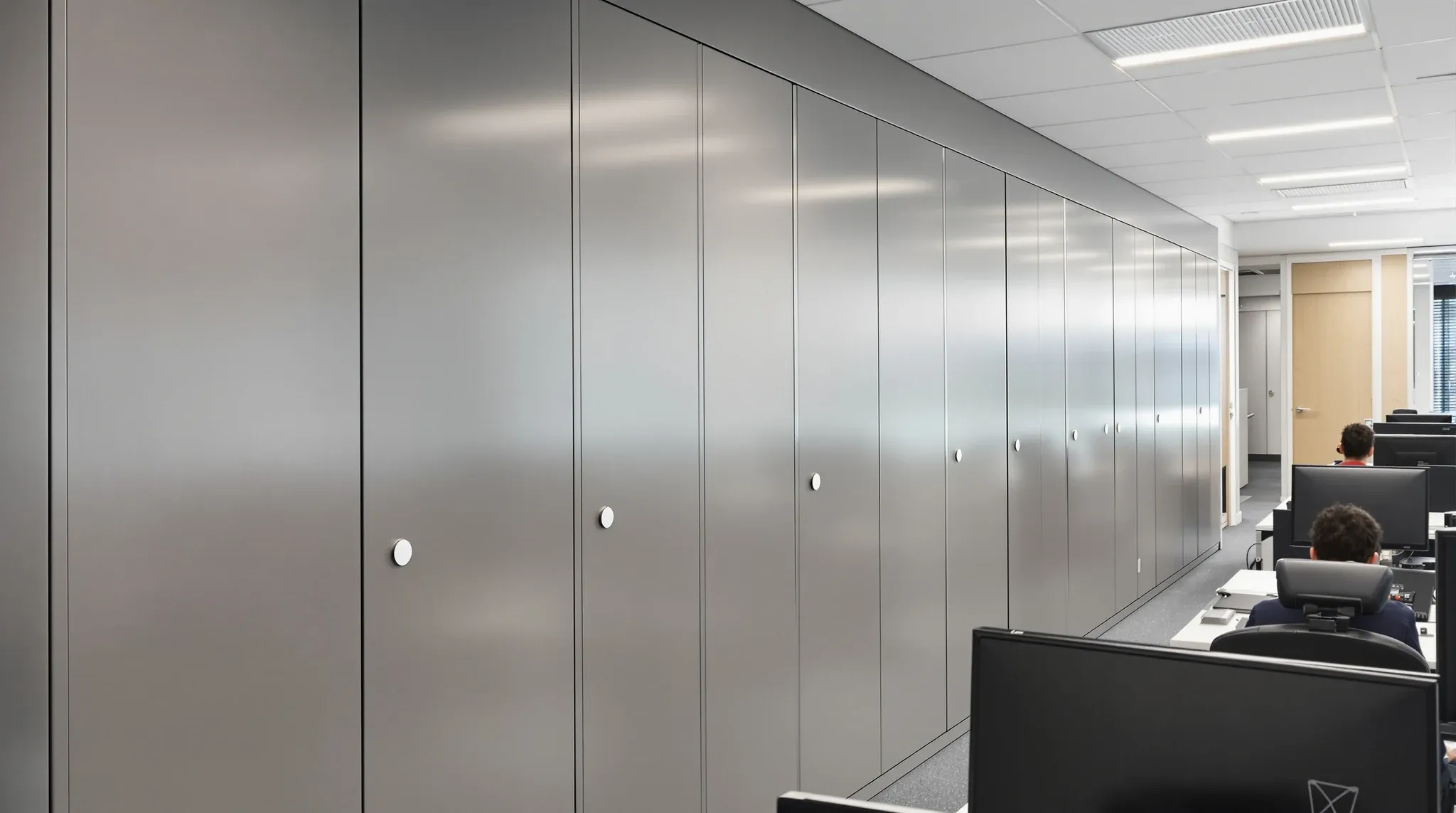 An accounting office in use with a long bank of closed grey compactus storage units along one wall