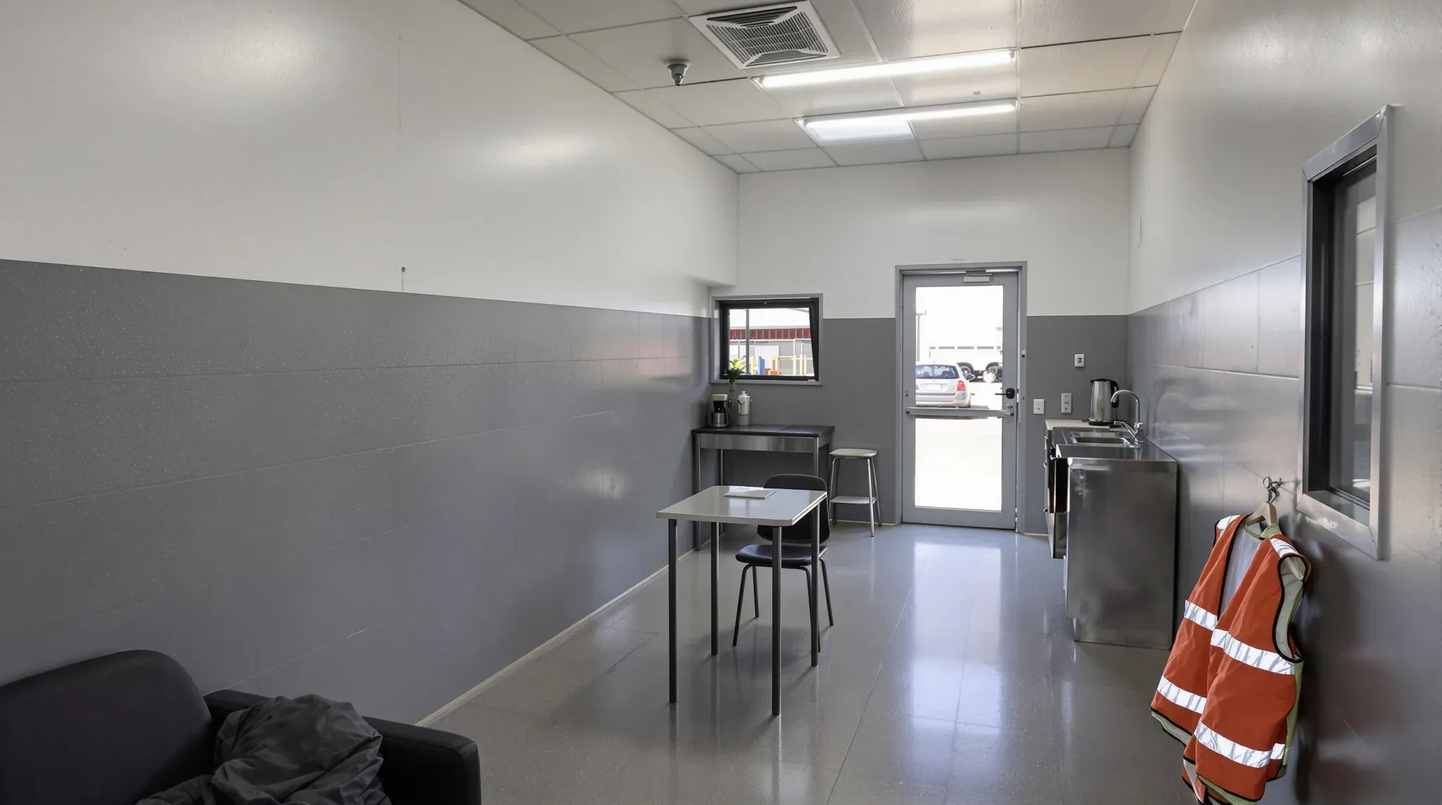 Depot drivers room with grey wall lining, a small table, a stainless kitchenette and a glazed door to the yard