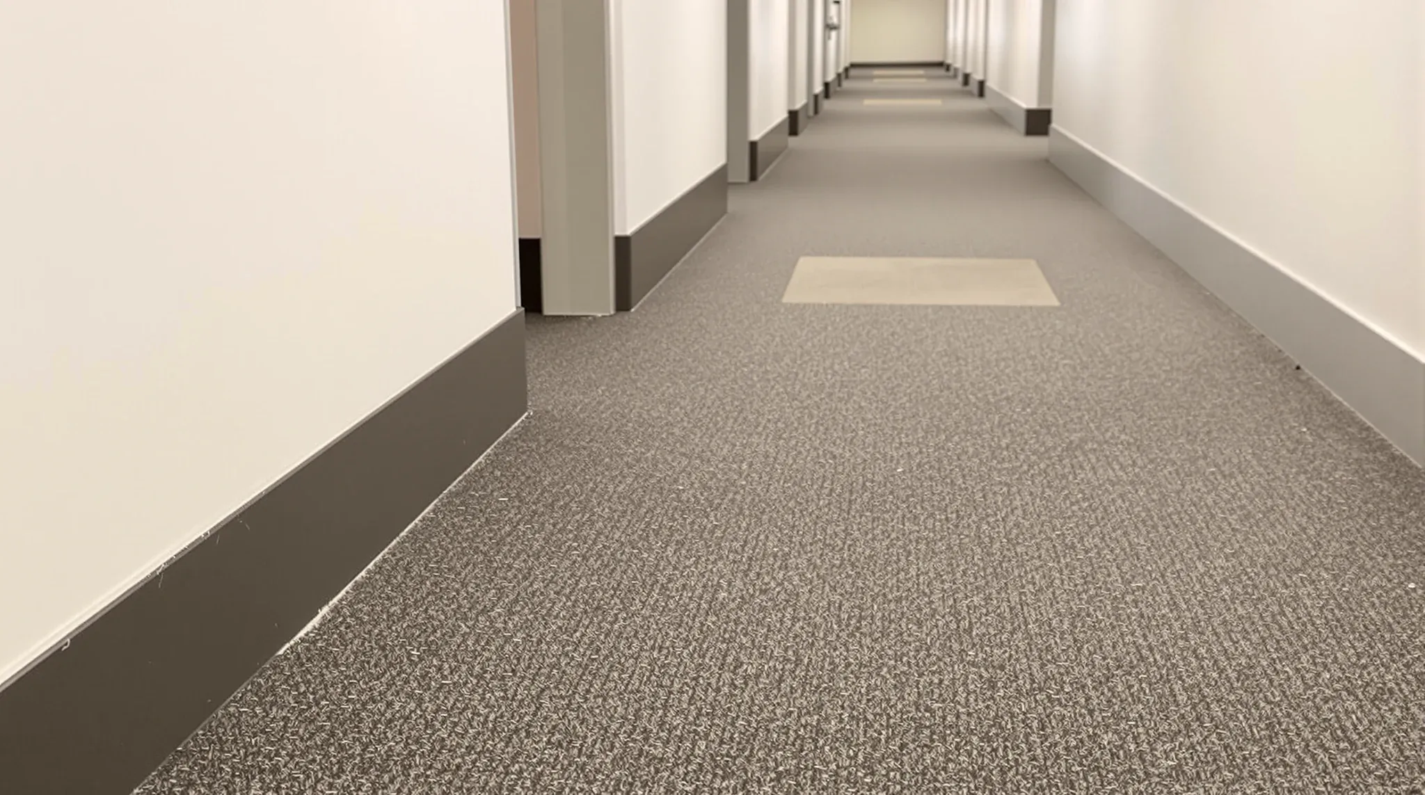 Ordinary scuffed skirting and worn carpet in a commercial office corridor at lease end