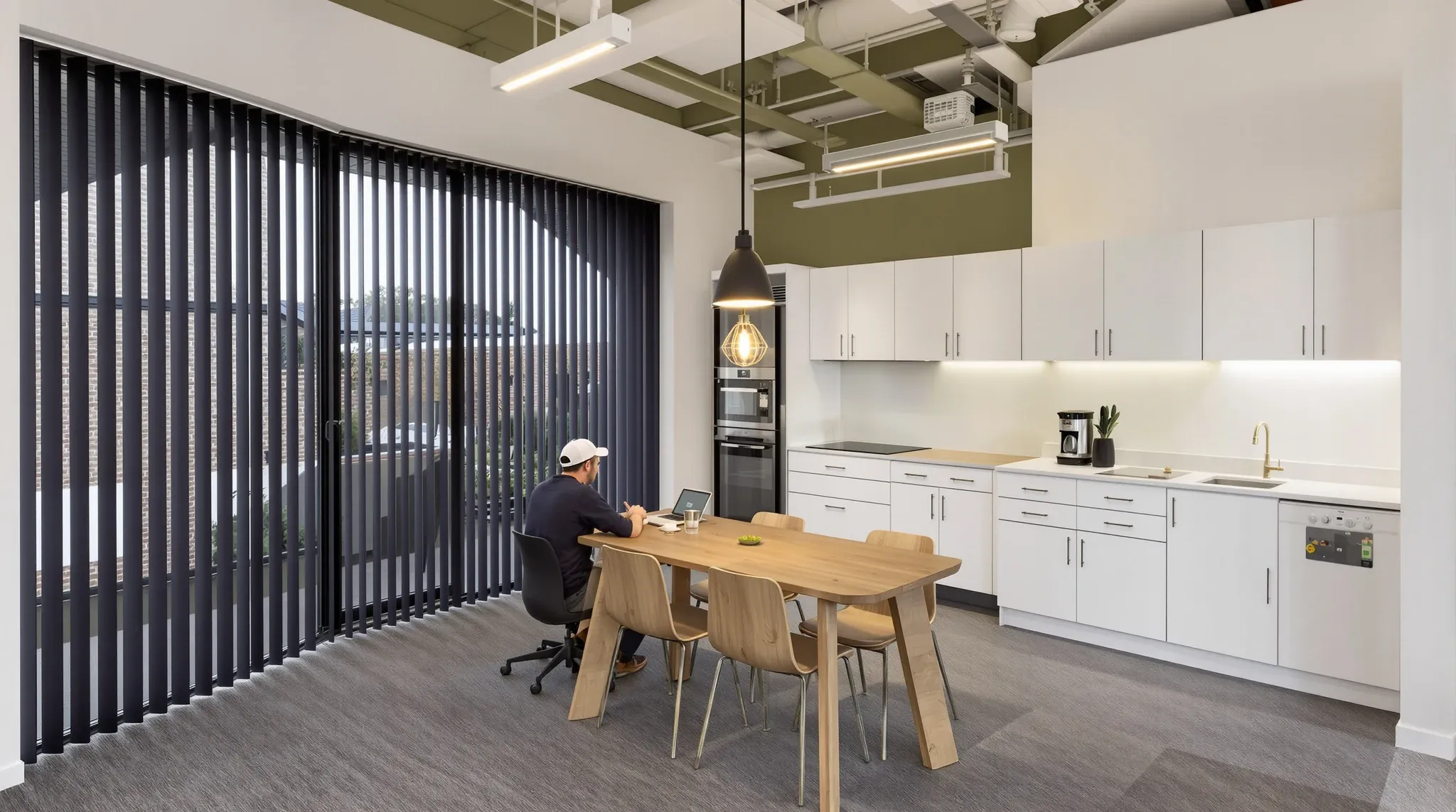 A small office for a growing business with a timber meeting table in the open and a plain kitchenette