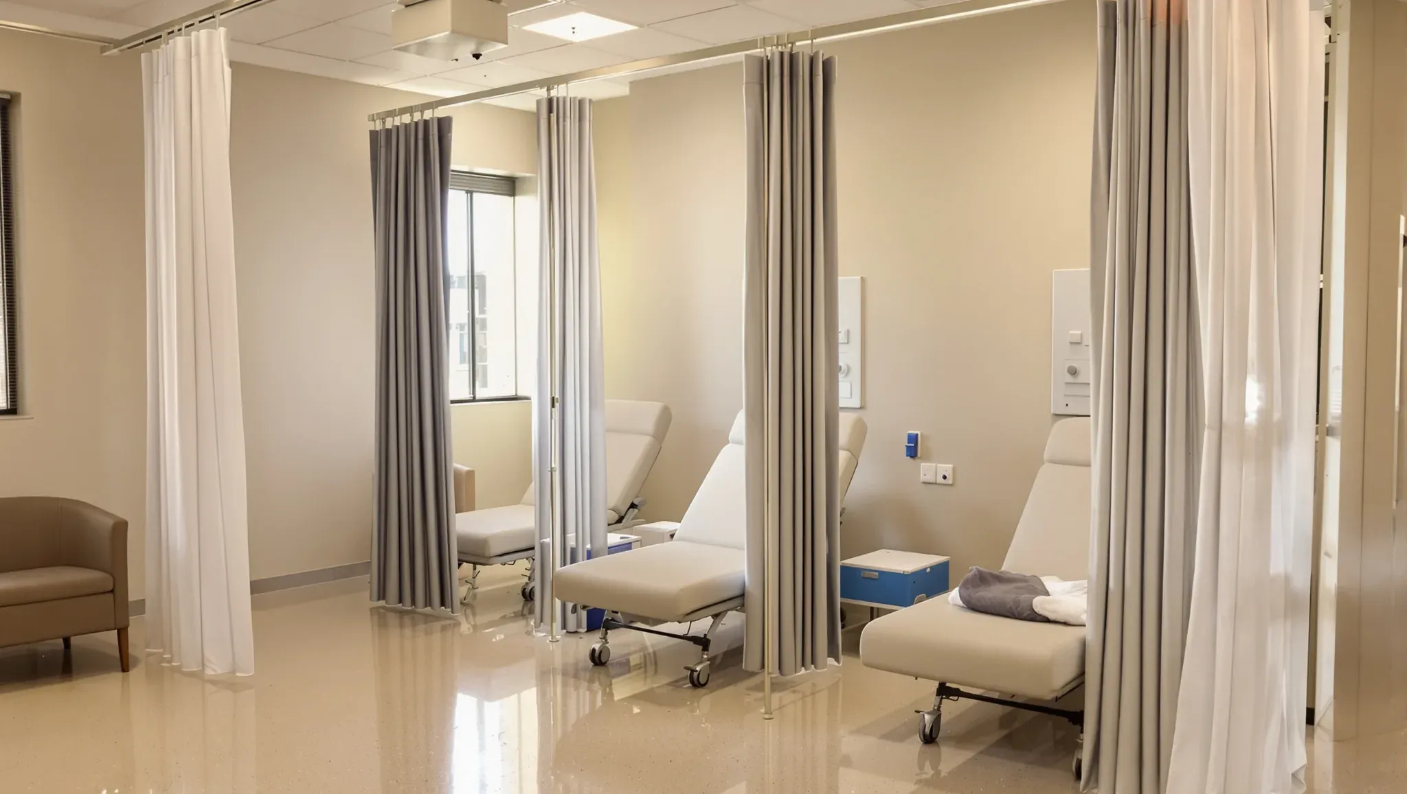 Recovery bays in a day procedure centre with recliner chairs, ceiling curtain tracks and a large window
