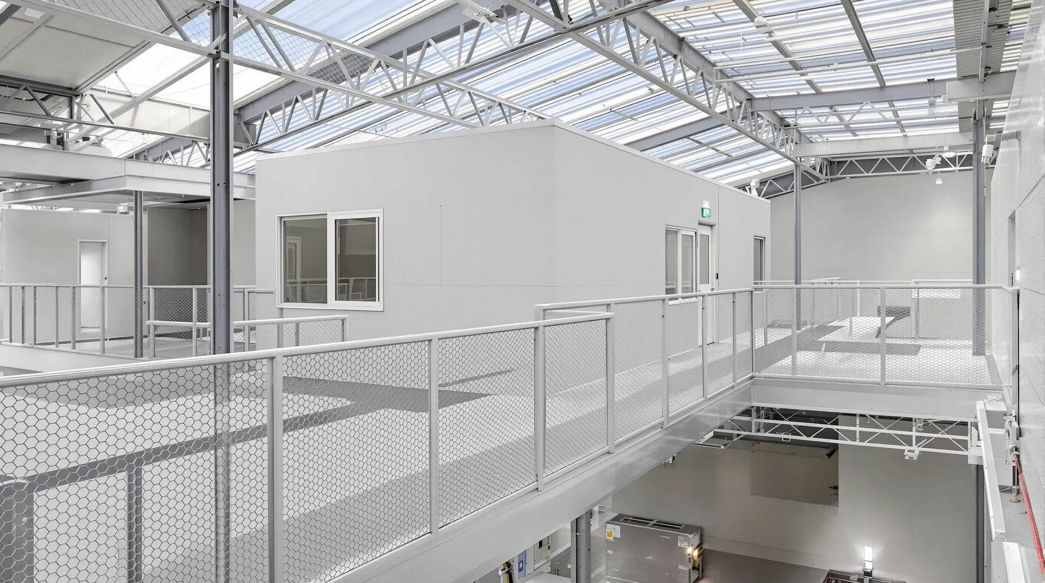 A mezzanine office with windows along a steel walkway inside a warehouse