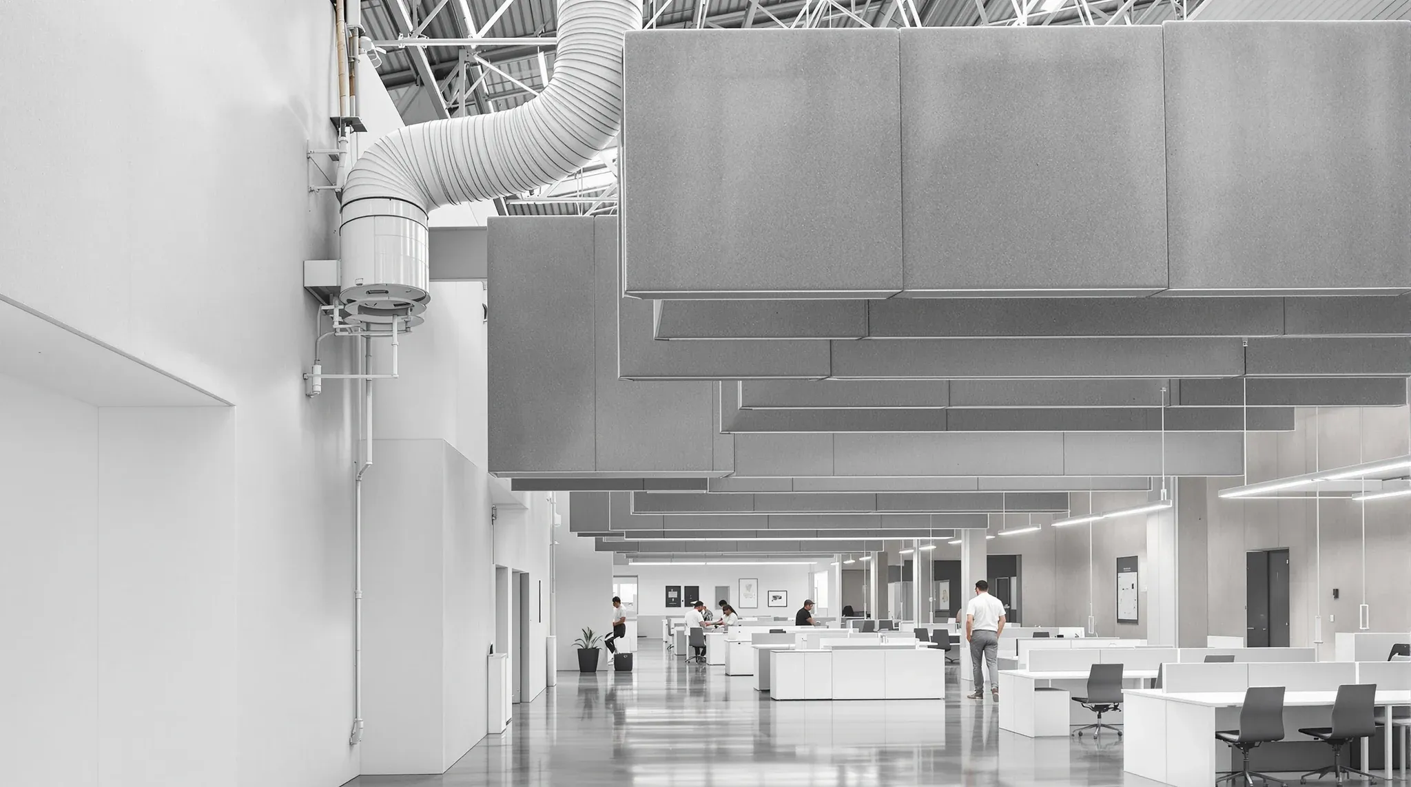 An office area inside an industrial unit with concrete walls, a high roof and felt acoustic baffles