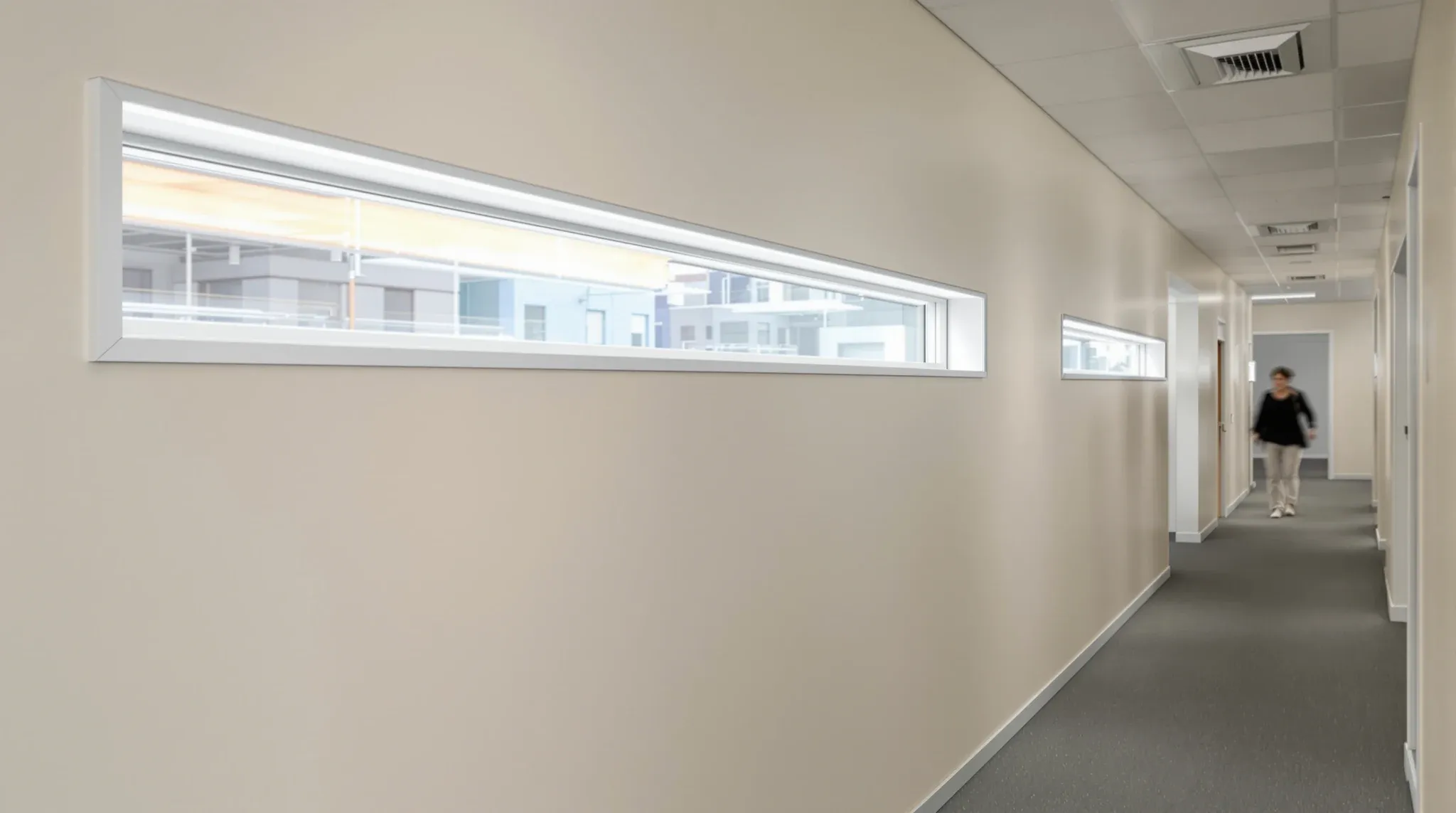 An internal corridor lit by a long high-level glass window set into a solid plasterboard wall