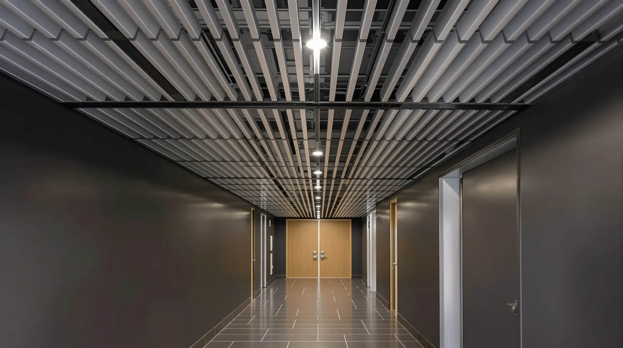 A corridor ceiling of long aluminium strips with dark shadow gaps and small downlights