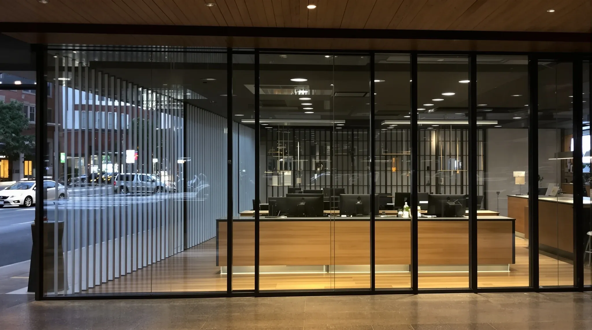 A real estate agency sales floor seen from inside the glass shopfront at dusk