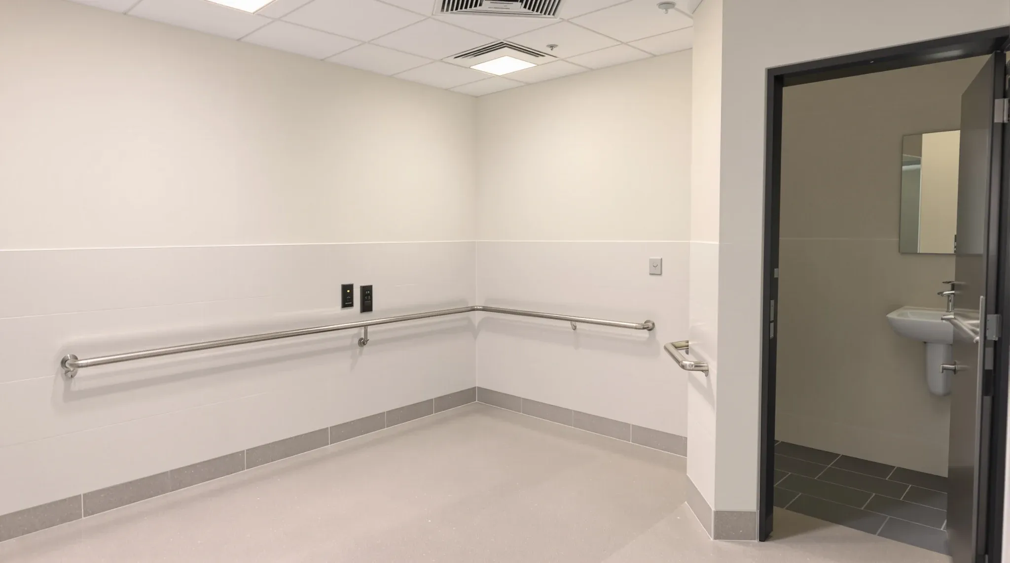Empty finished accessible bathroom in an office, grab rails, tiled walls, no signage