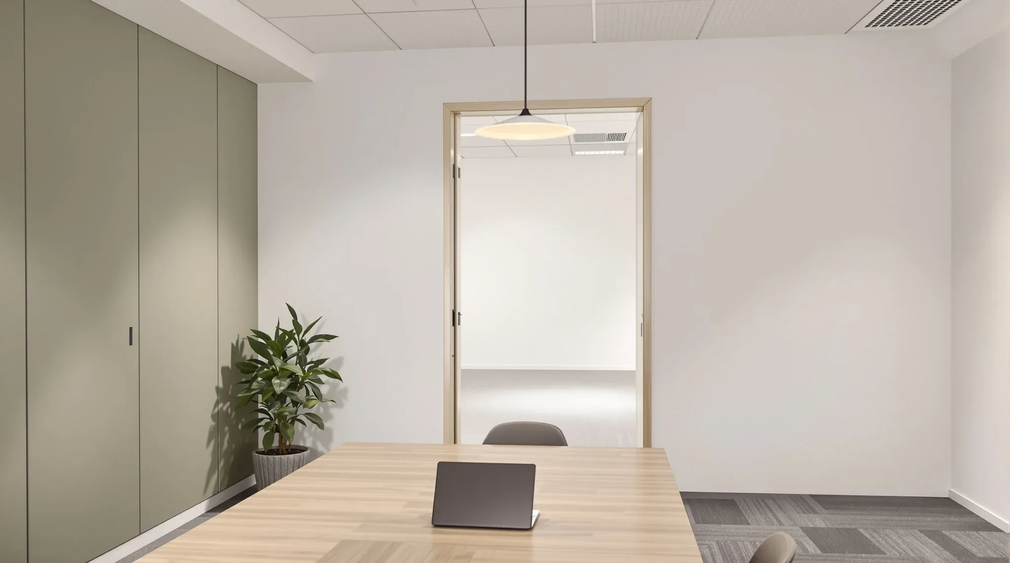 A renovated office in use, looking through an open doorway into an empty, plain area next door